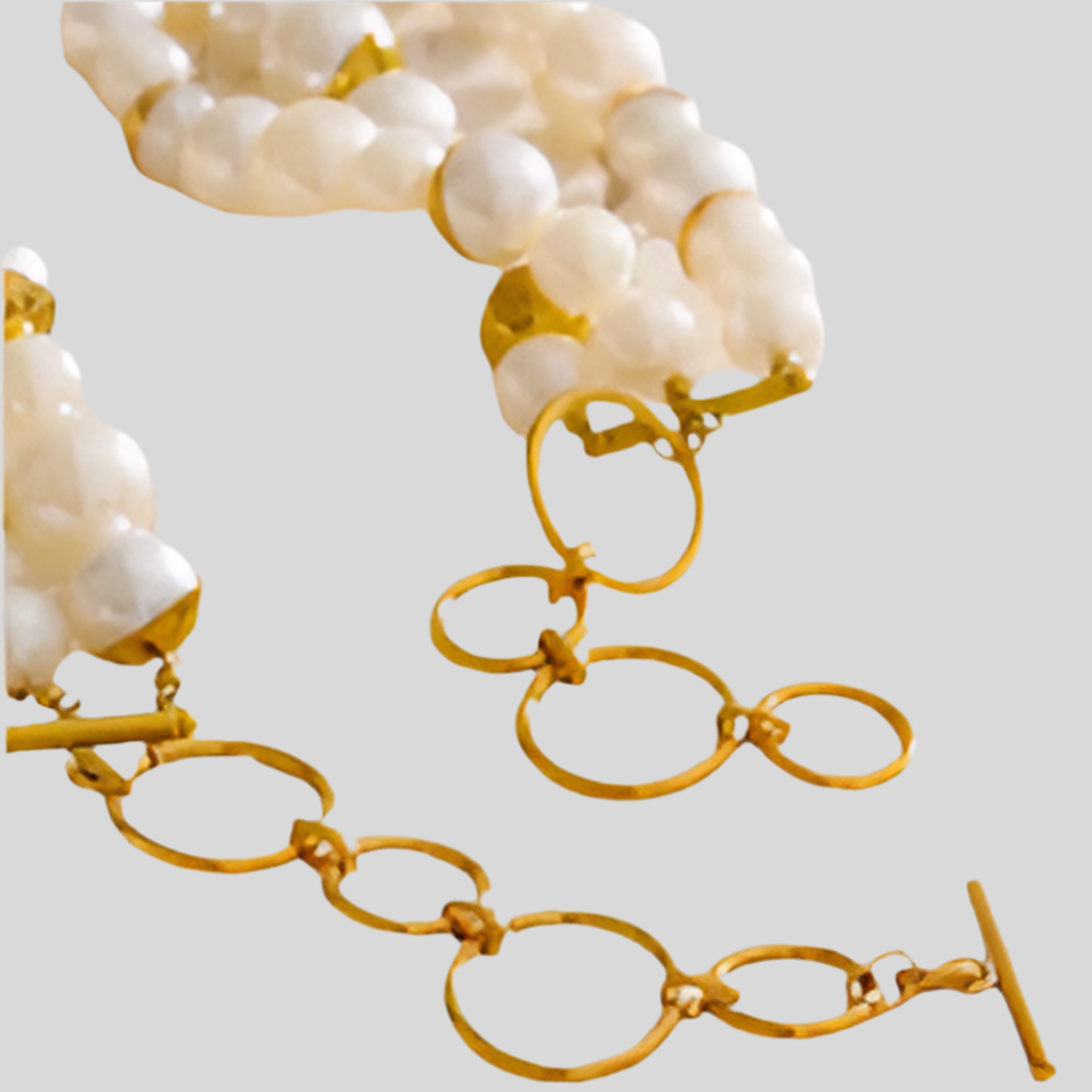Gold chain necklace with white pearls on a light gray background