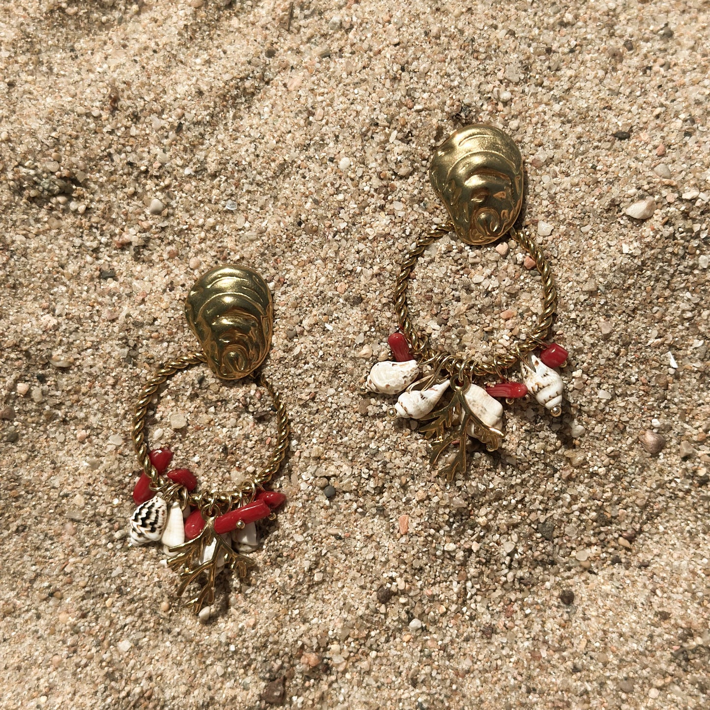 Pair of gold hoop earrings with charms on a textured surface