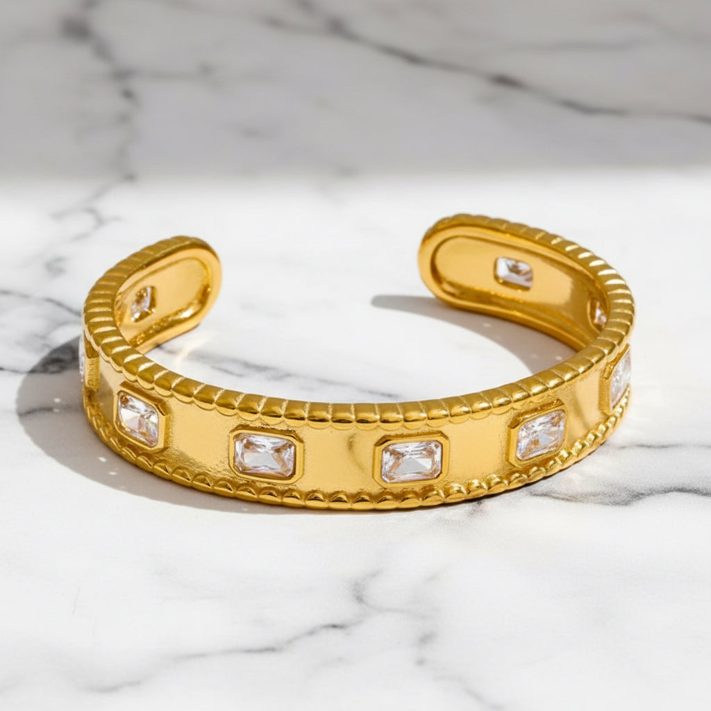 Gold bracelet with embedded crystals on a white background