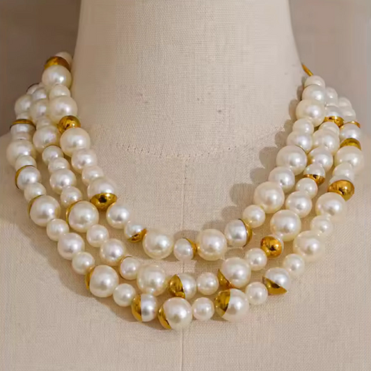 Pearl necklace with gold accents on a mannequin bust against a beige background