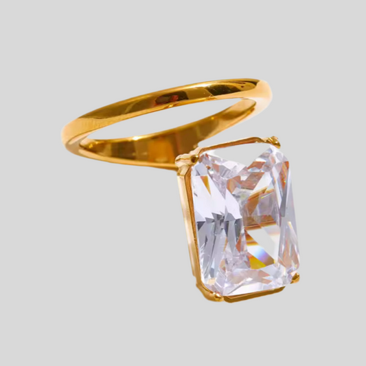 Gold ring with a large clear gemstone on a light gray background
