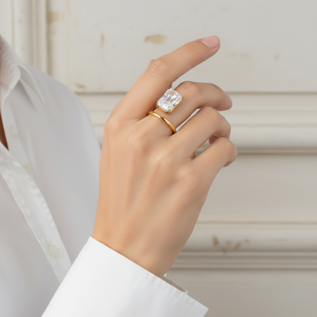 Hand wearing two diamond rings on a plain background