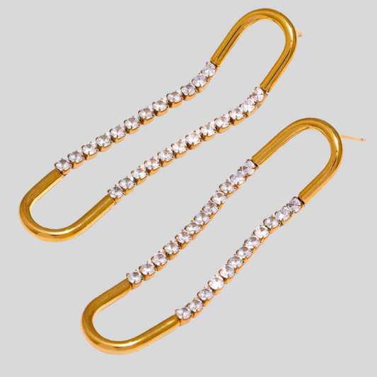 Gold earrings with clear gemstones on a light gray background