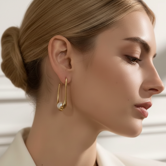 Close-up of a woman wearing gold hoop earrings with a pearl accent.