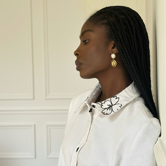 Woman wearing a white blouse with a decorative collar in a neutral setting