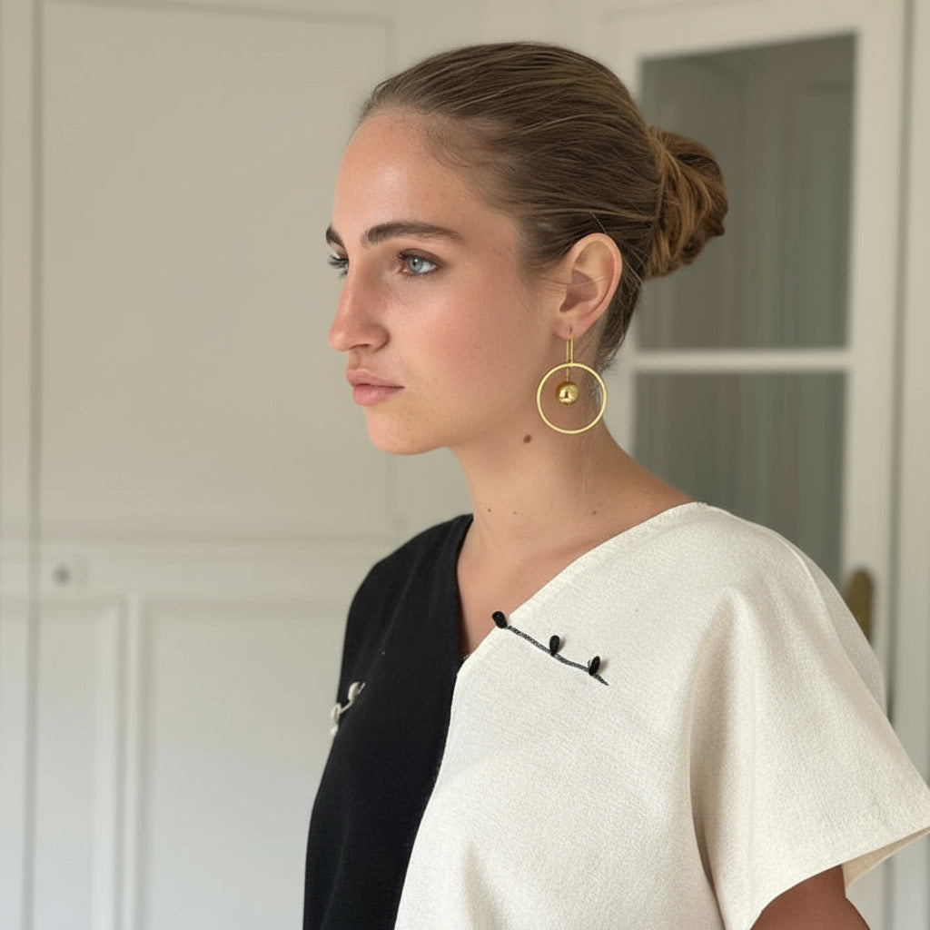 Woman wearing a white top with black accents in a room with white walls.