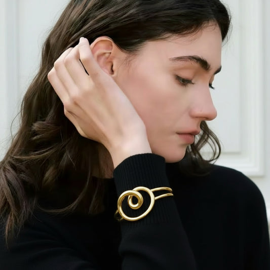 Woman wearing a gold bracelet with a dark background