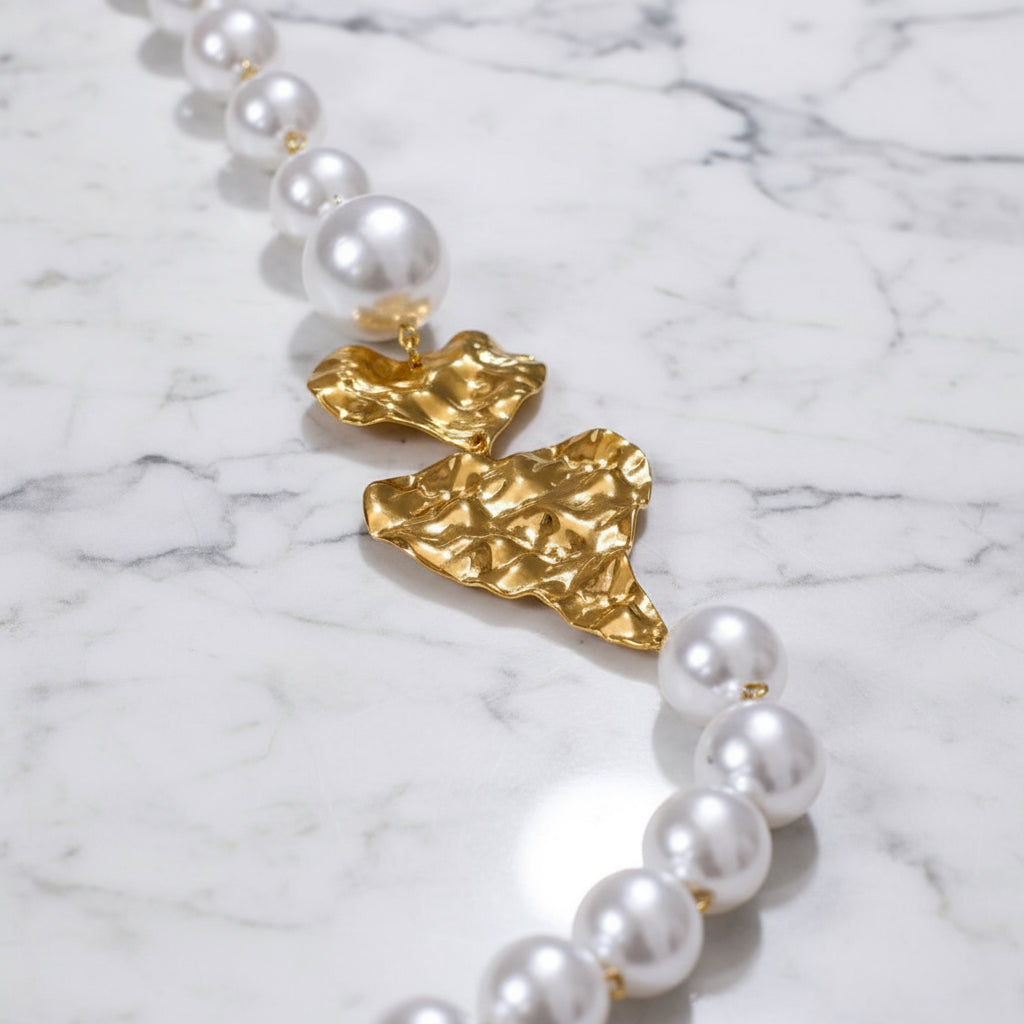 Gold and pearl earring on a light gray background