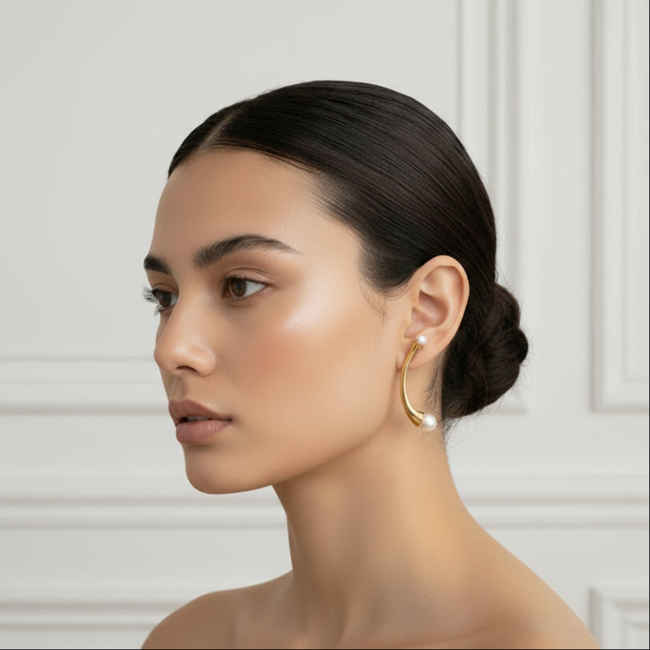 Woman with elegant hair and earrings in a stylish room with white walls and furniture.