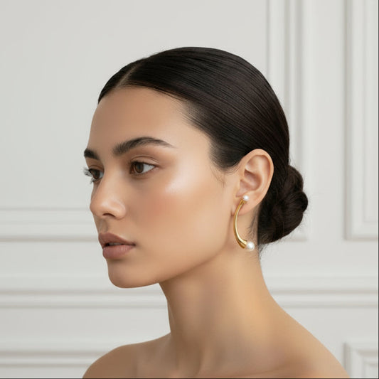 Woman with elegant hair and earrings in a stylish room with white walls and furniture.