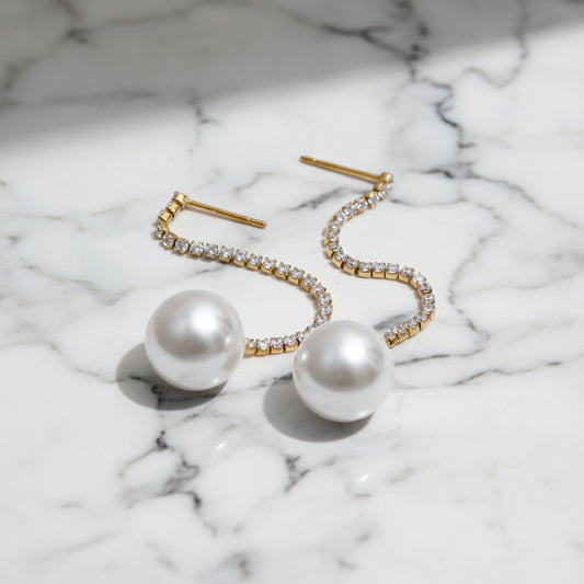 Pearl earrings with gold accents on a marble table background