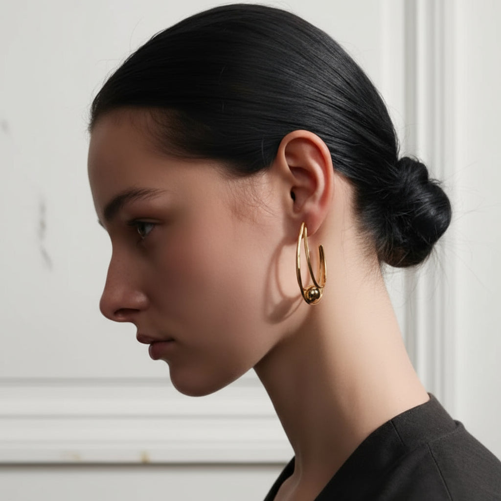 Woman wearing gold hoop earrings with a neutral background