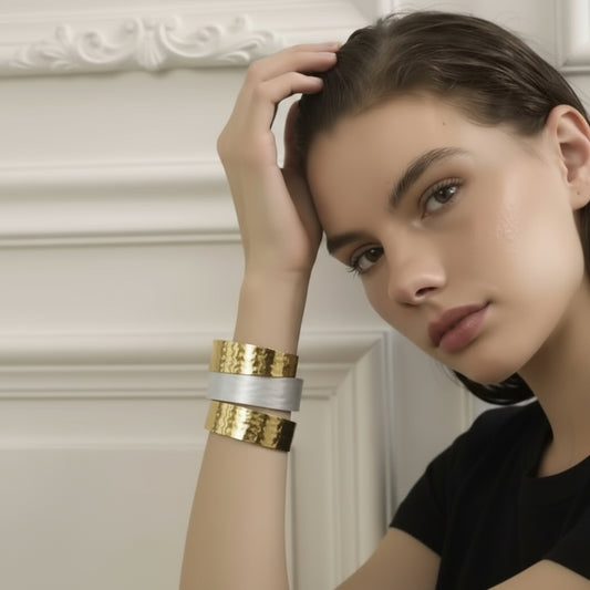 Woman wearing gold and silver bracelets on a plain background