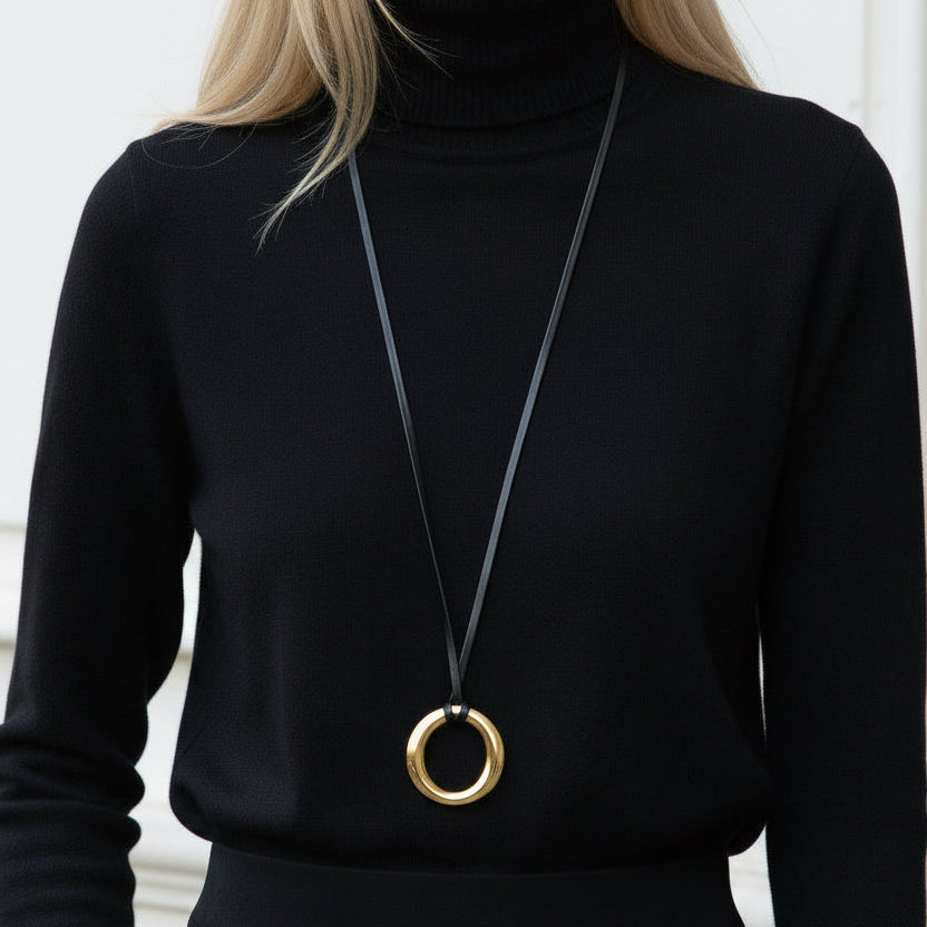 Person wearing a black turtleneck and a long necklace with a gold pendant.