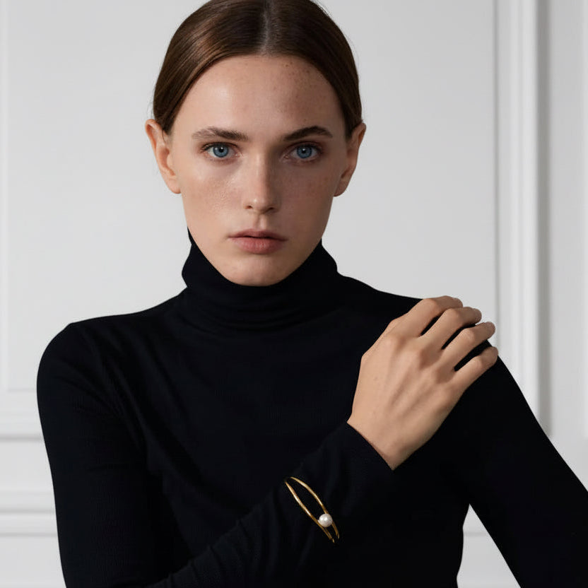 Woman wearing a black turtleneck sweater against a white wall